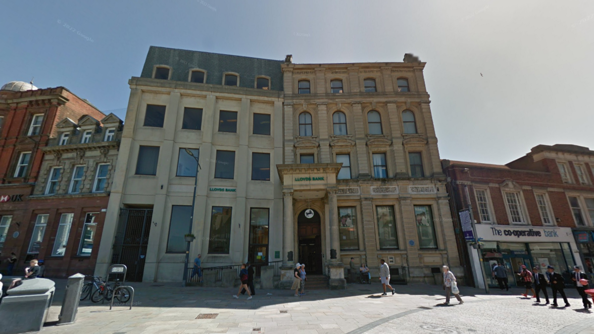 An old-style four-storey building next to a new four-storey building in a high street setting