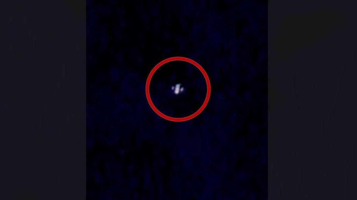 An image of an alleged drone caught on camera in the night sky above New Jersey. A red ring is around it