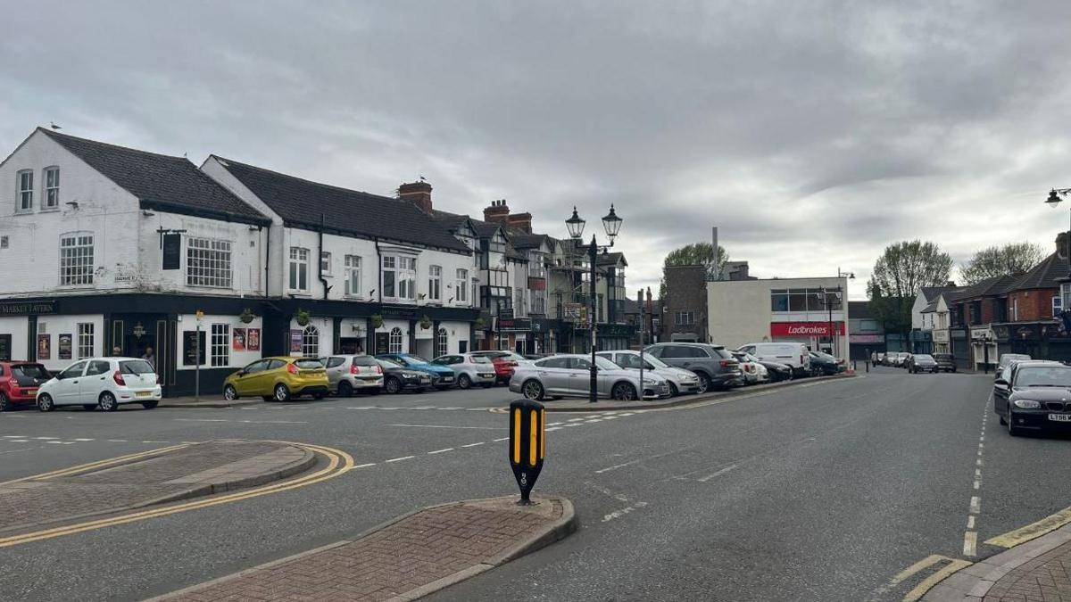 Cleethorpes Market Place with several parked cars surrounded by shops