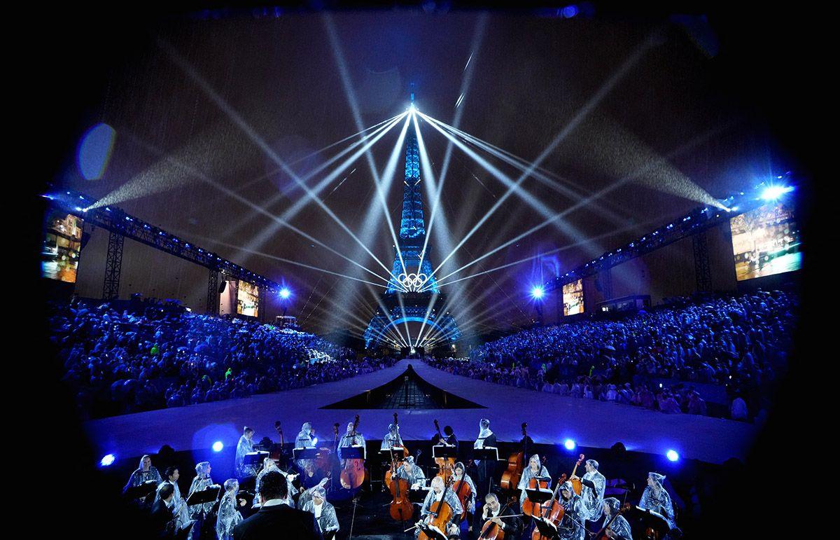 The Eiffel Tower is illuminated with lights and lasers and the Olympic sign with an orchestra in foreground, during the opening ceremony of the Paris 2024 Olympics.