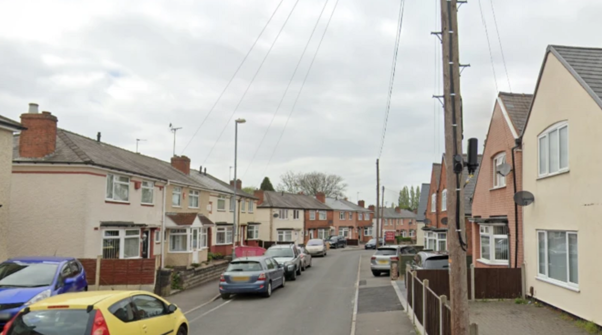 A residential street with houses and cars along both sides