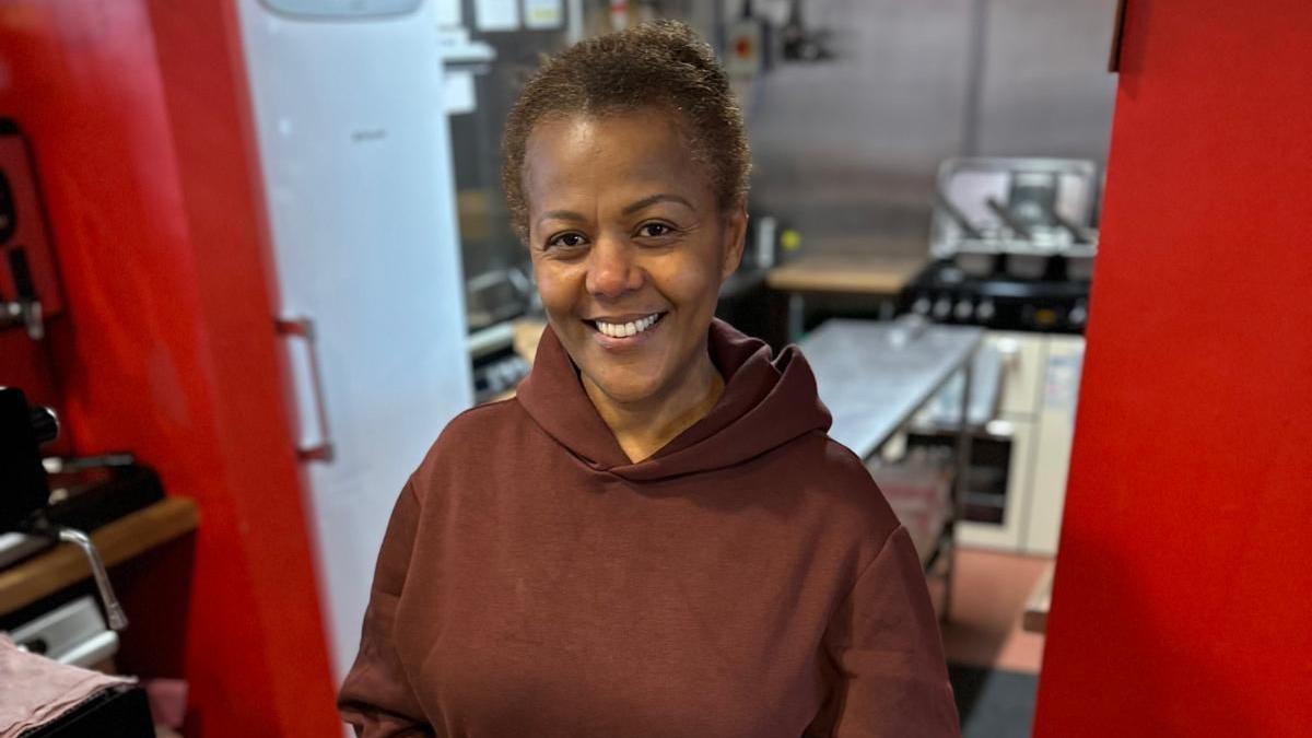 Tutu Melaku stood in her restaurant behind a counter smiling at the camera.