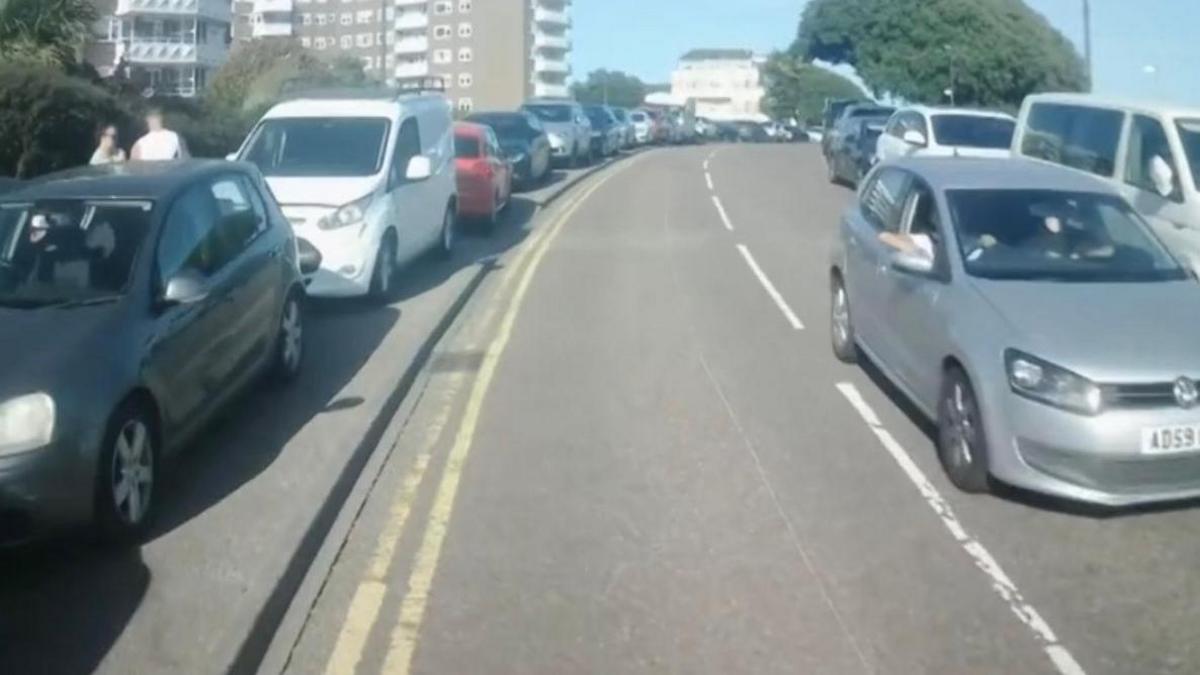 A number of vehicles can be seen, parked illegally next to double yellow lines