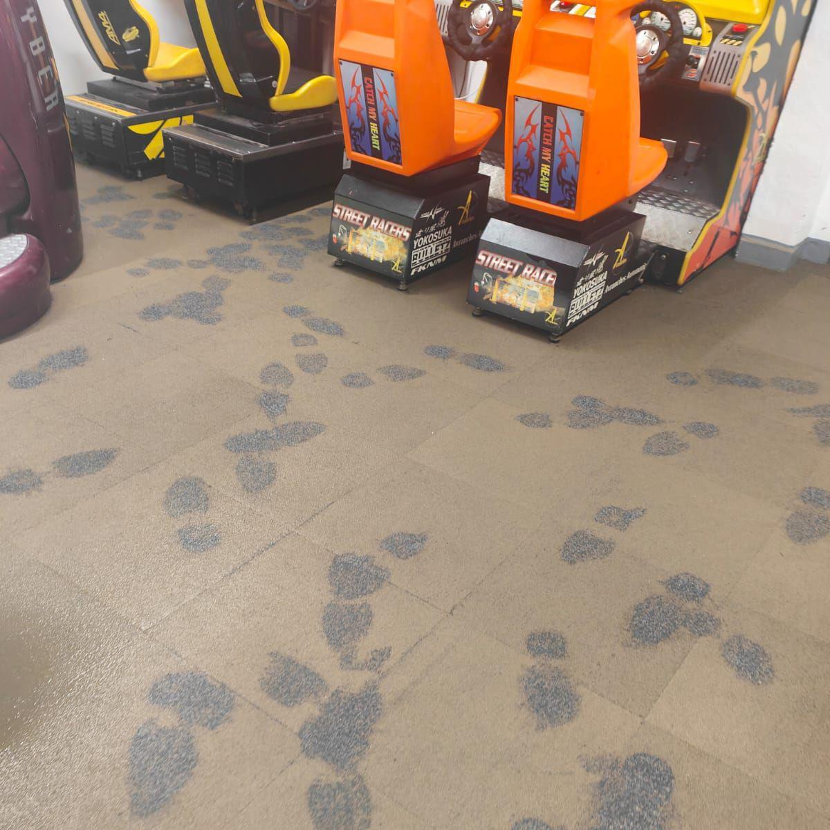 Footprints in the mud left on the floor near to the Street Racers arcade machine