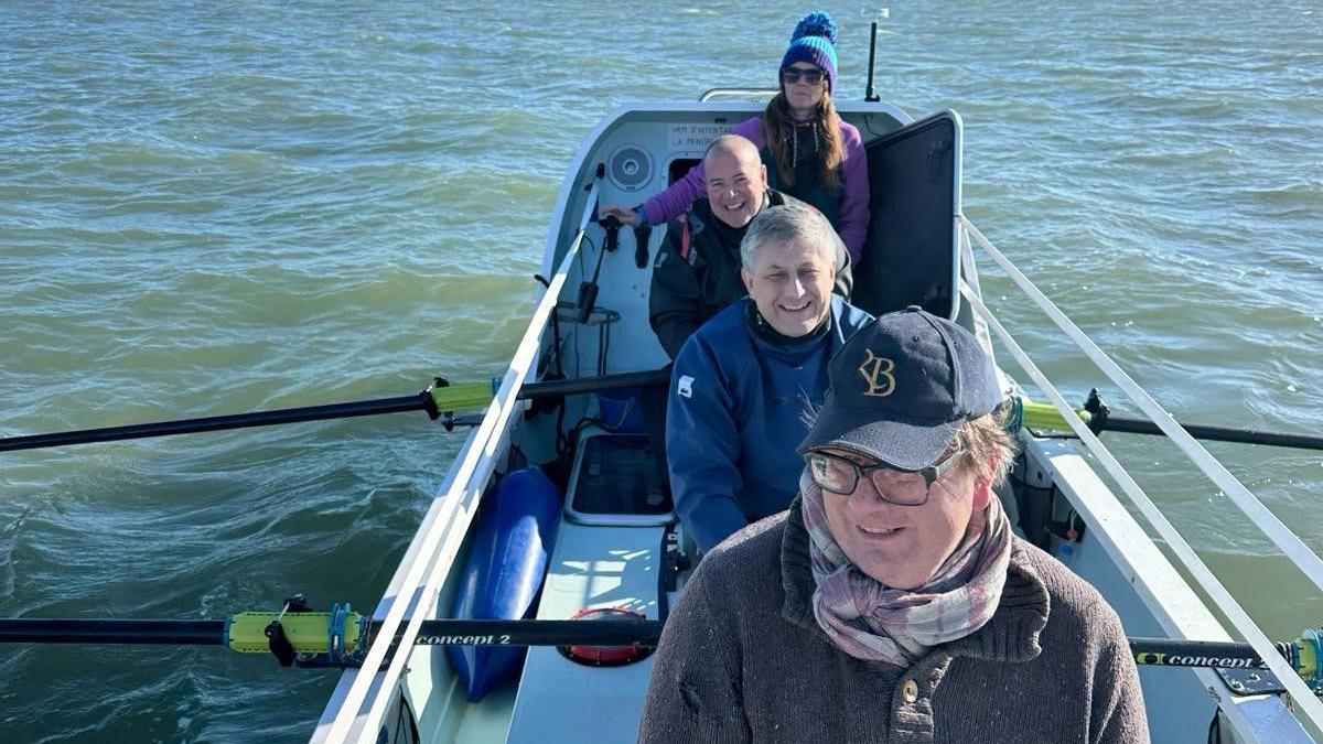 Three men and a woman in a rowing boat