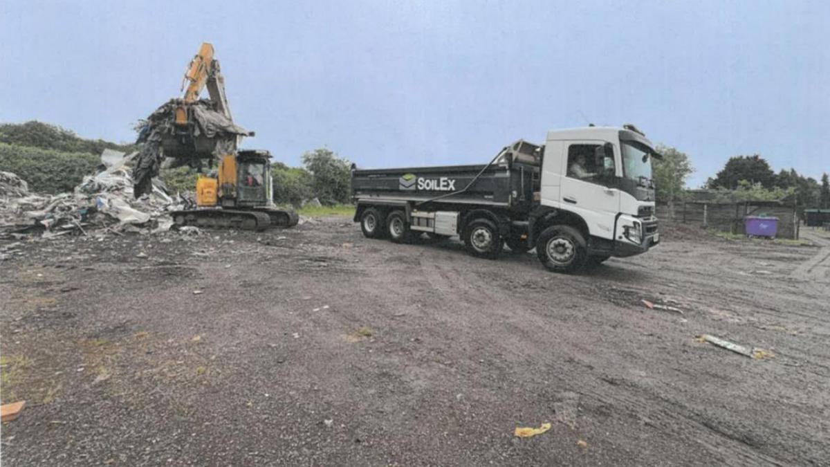 A digger loads waste into a SoilEx branded truck