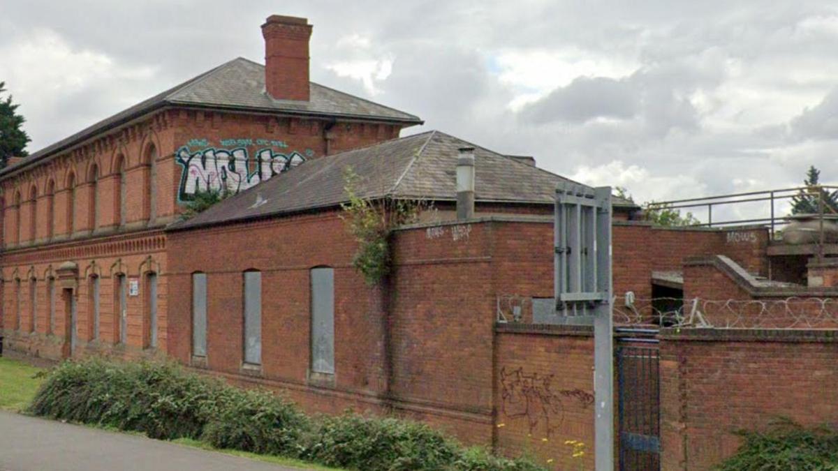 Two-storey brick building with arched windows. Large graffiti letters are visible on the exterior of the first floor.