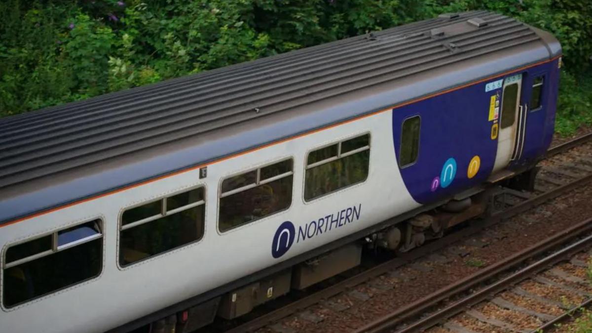 Aerial view of a blue and white Northern train on railway tracks.