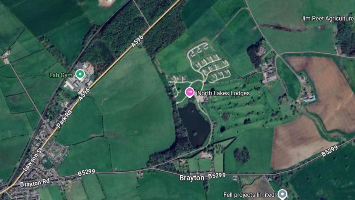 A Google Maps screenshot showing an aerial view of the location where North Lakes Lodges is. It is on a parcel of land between the A596 and the B5299. The area is mostly surrounded by green space.