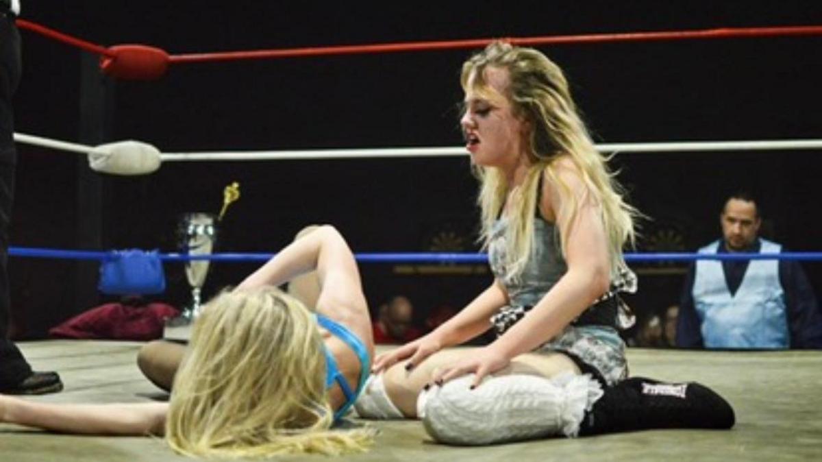 Annabelle on the floor leaning over an opponent in the ring looking out of breath. 