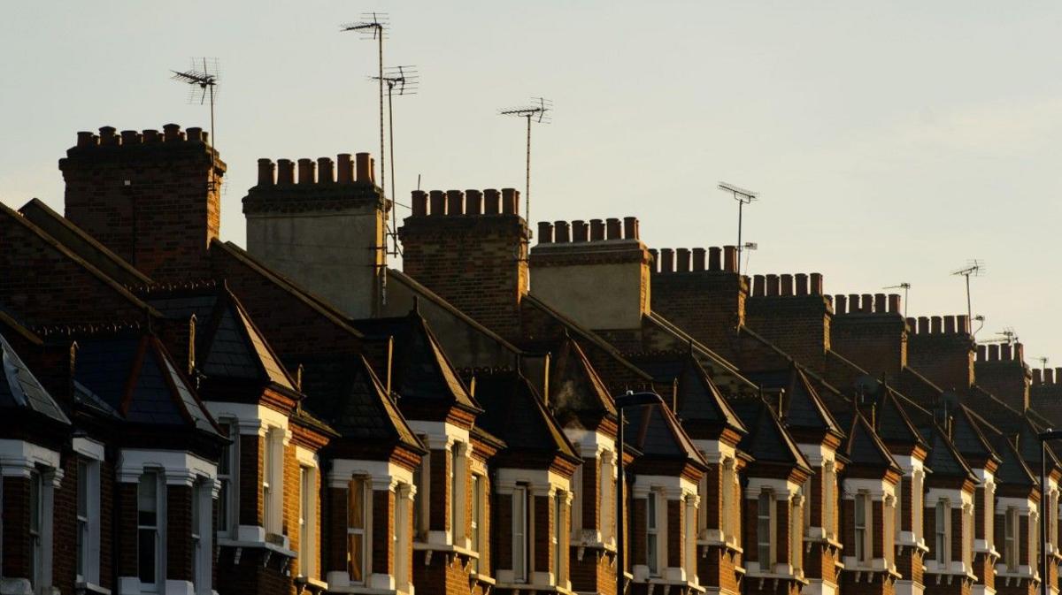 Ten chimneys and more than half a dozen TV aerials are on the top of homes in this generic image. Windows on an upper floor are visible.