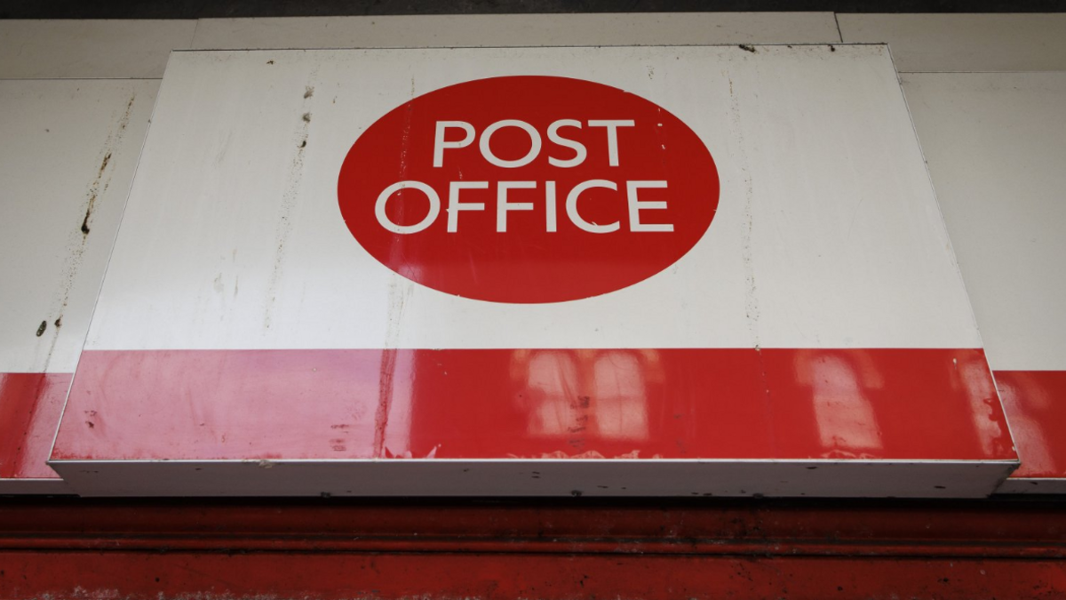 An exterior view of the sign on a branch of the Post Office showing the company logo on a white background and a red stripe along the bottom of the sign