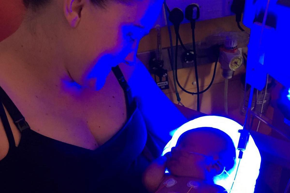 Steph cradles her baby boy Aiden. He has wires and tubes attached to him.