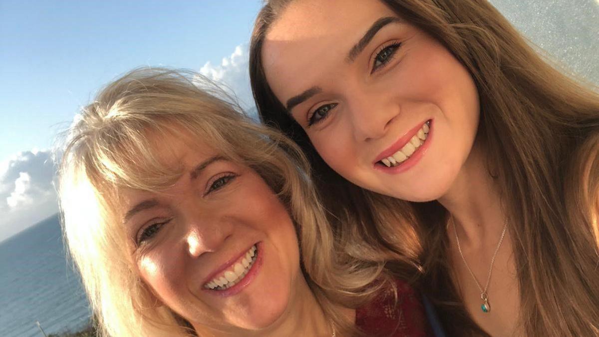 Two women smiling at camera in front of the sea