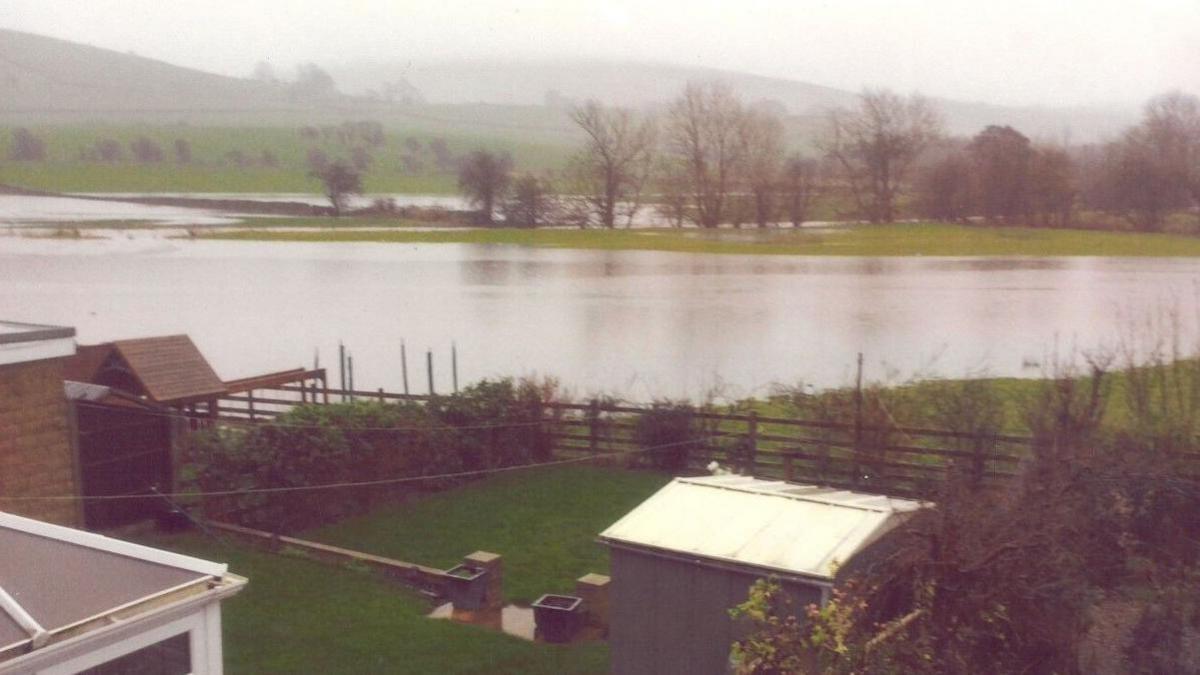 A photograph showing previous flooding in Earby, Lancashire. A large expanse of standing water can be seen lying on grassland, coming up to the boundary of residential properties.