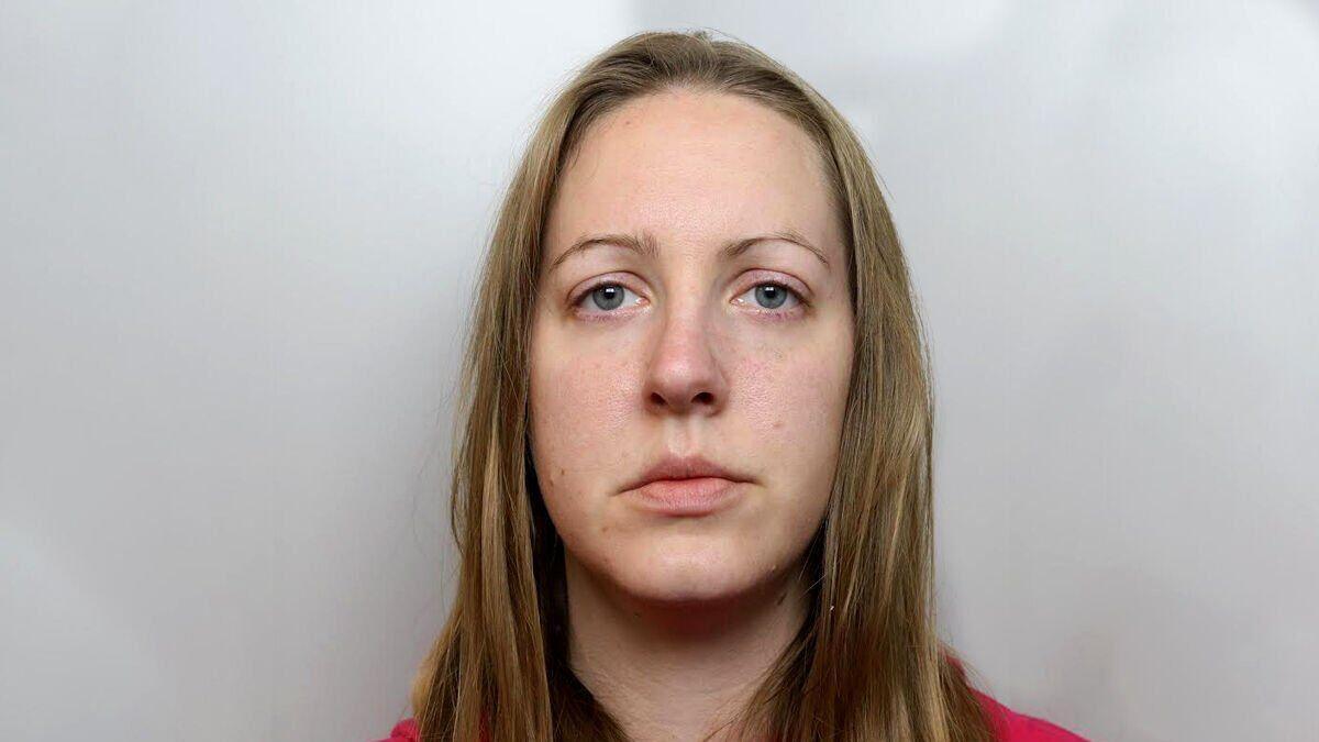 Lucy Letby mugshot in red hoody - medium length brown hair and blue eyes with thin eyebrows