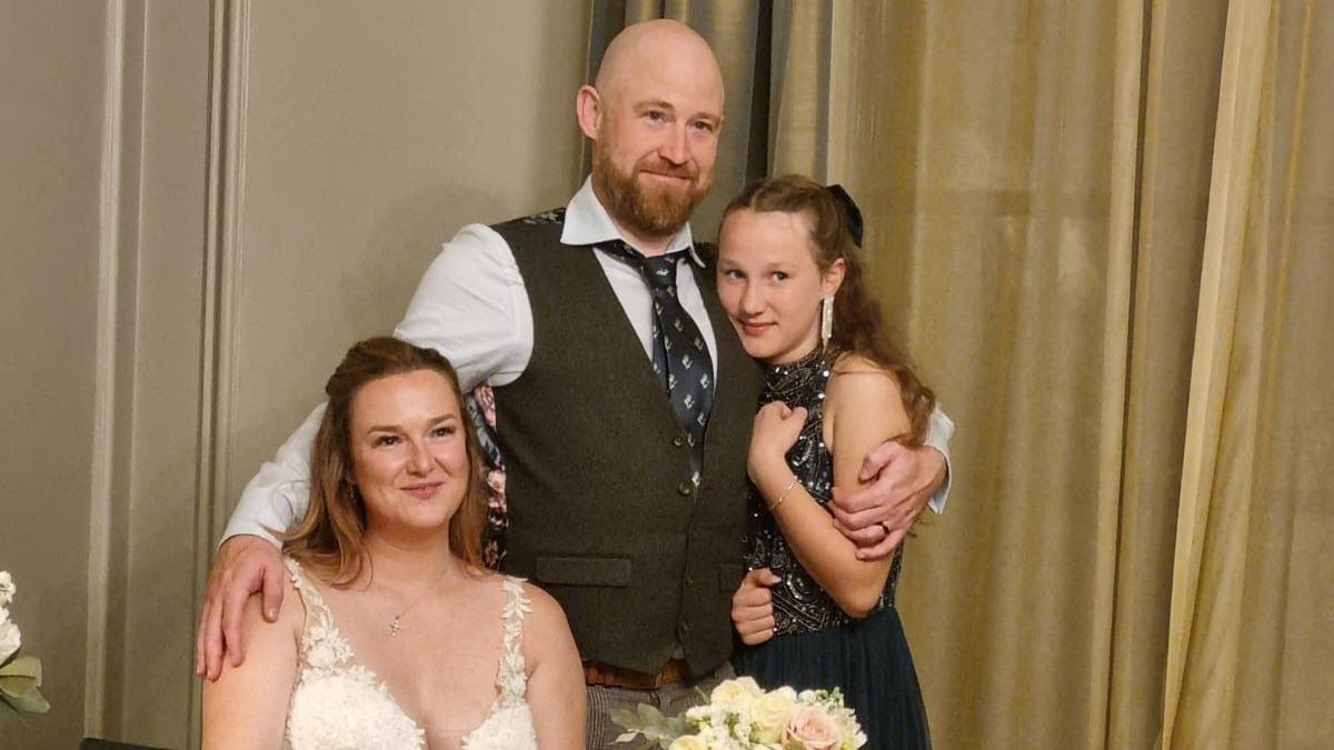 Daniel Mason poses with his arm around his new wife Danielle Mason and his step-daughter inside the Old Marylebone Town Hall