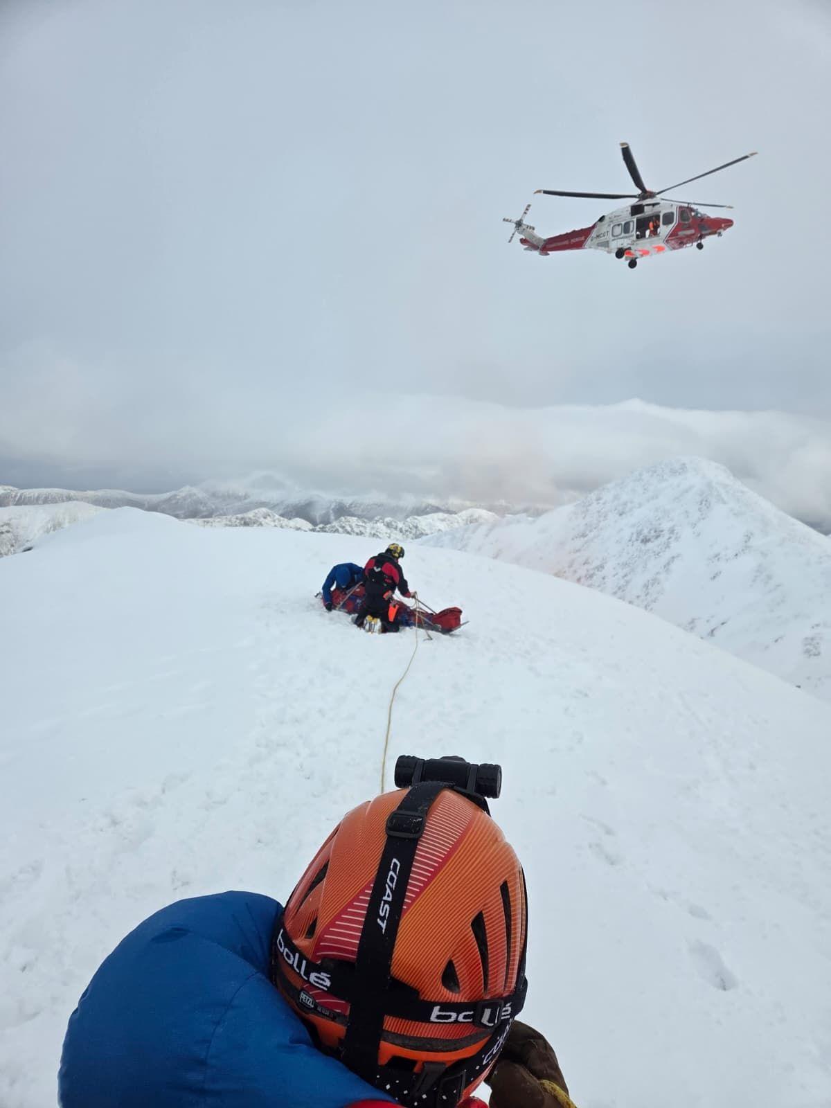 Heileacoptar nam Maor-Cladaich os cionn luchd-teasairginn a tha a' cuideachadh an fhir-sreap a bh' ann an cruaidh chàs