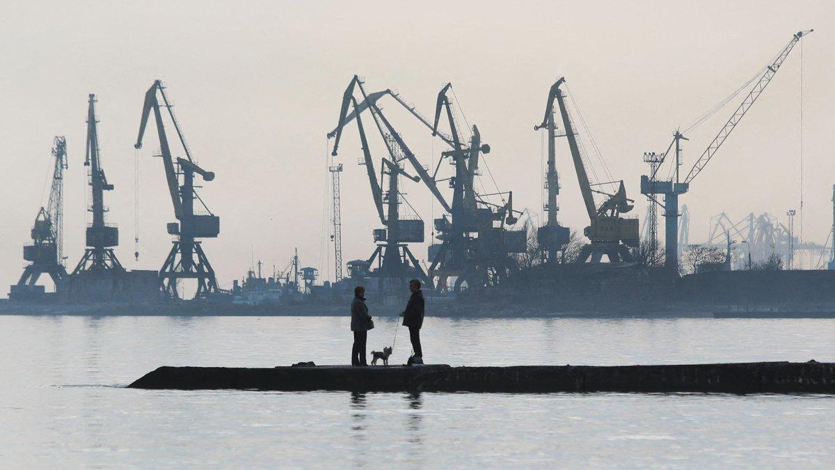 A couple walks a dog on a pier at a coast of the Sea of Azov in Ukraine's industrial port city of Mariupol on February 23, 2022