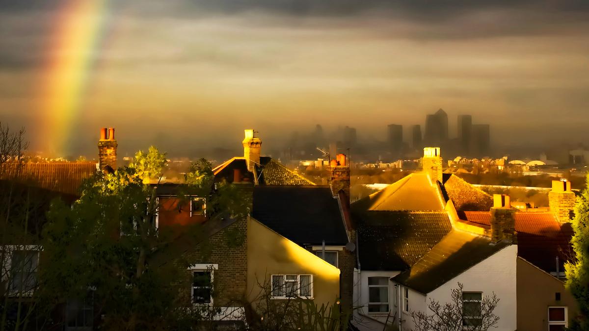 Rainbow over the rooftops of London, with Canary Wharf in the distance