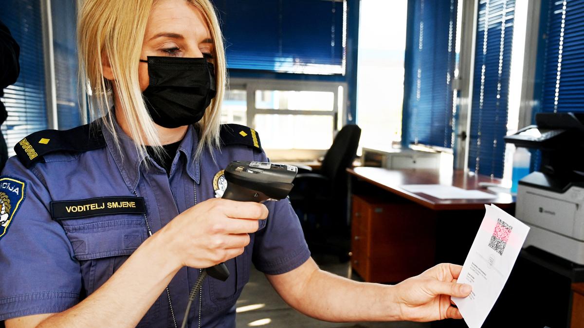 Police officer at the Bregana border crossing between Croatia and Slovenia scans QR code on an EU digital Covid passport