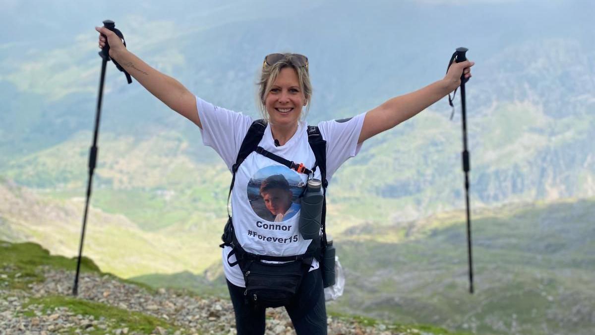 Clair Todd at the top of Snowdonia with poles in the air 