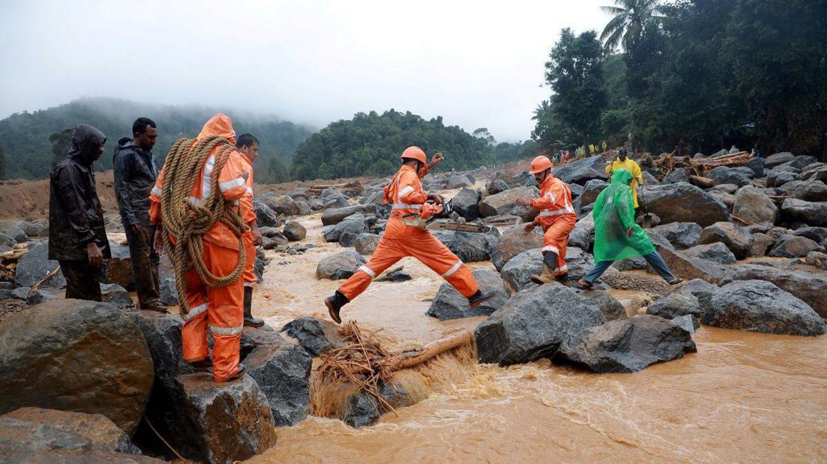 Members of rescue teams move towards a landslide site after multiple landslides in the hills in Wayanad