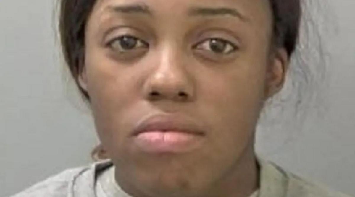 A mug shot of a woman with dark hair tied back and wearing a light grey top