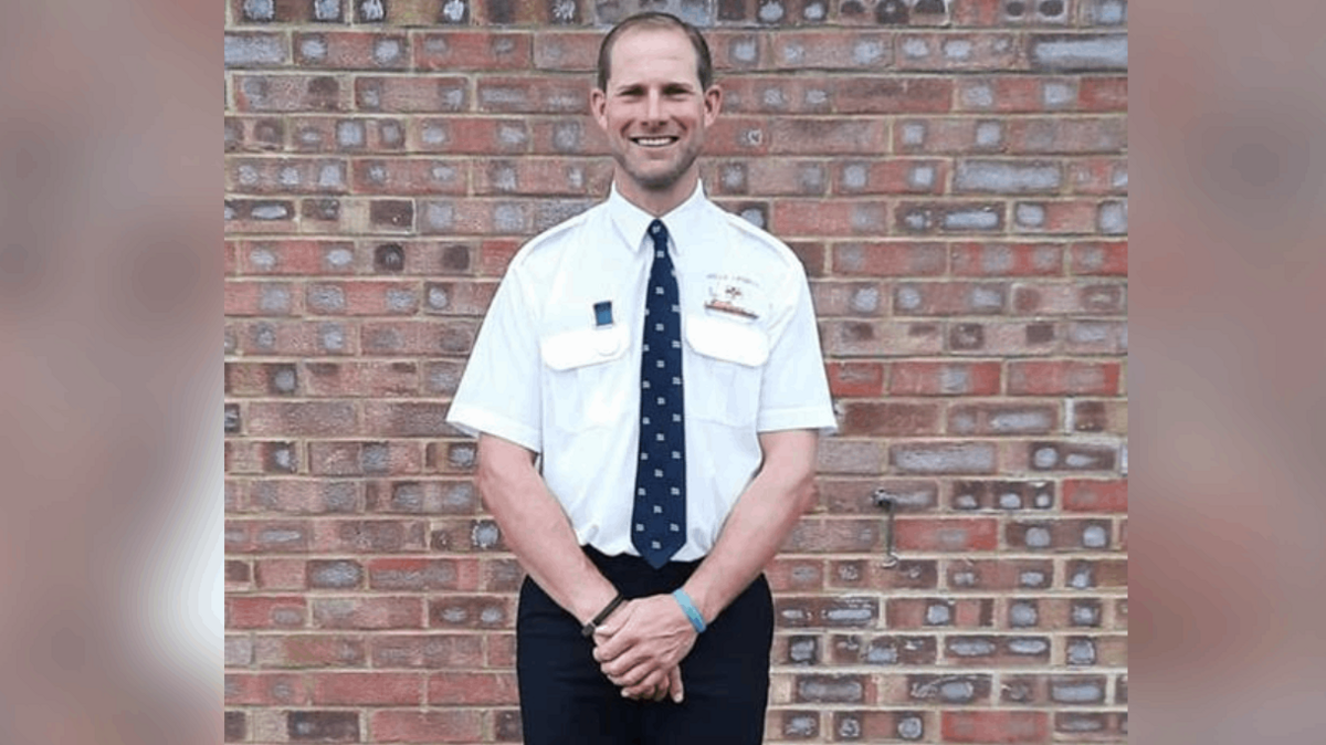W.G Cooper's grandson standing hand in hand in his RNLI uniform-a shirt and tie. He is smiling.
