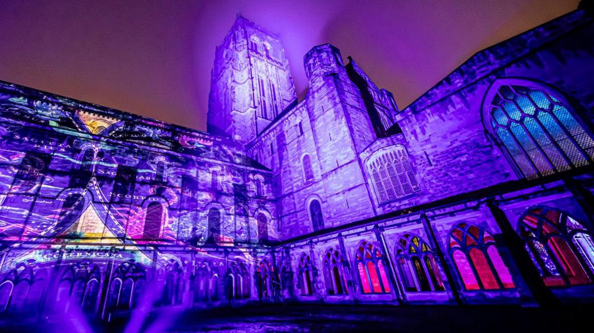 Projections on Durham Cathedral's exterior. It is light up in blue, purple and pink. 