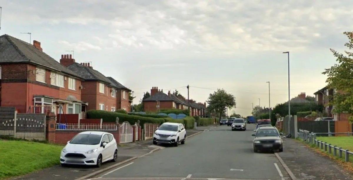 A screengrab from Google street view of a residential street with cars parked on either side. 