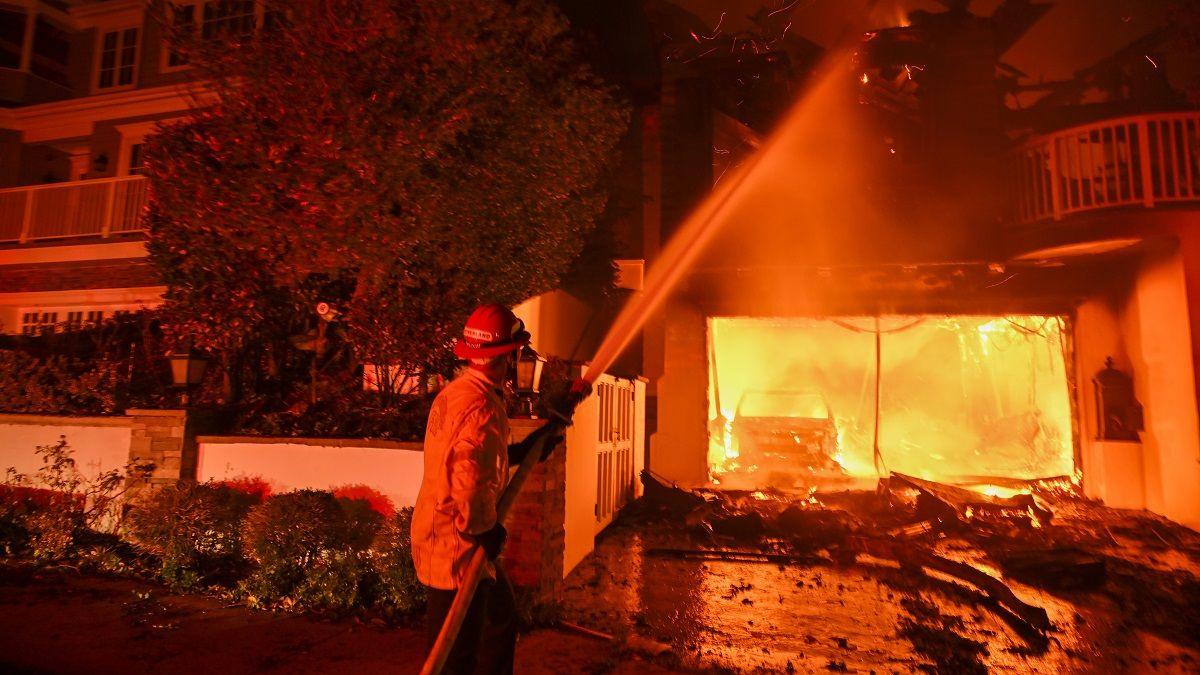 A firefighter douses a building on fire