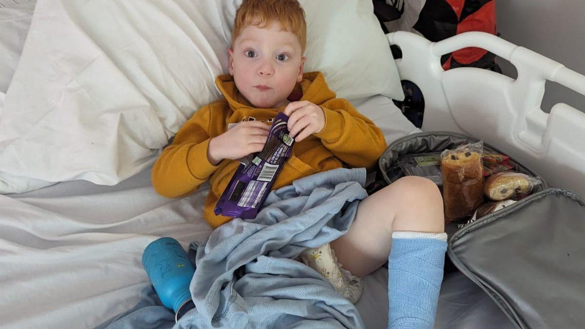 Billy sitting on a bed eating chocolate