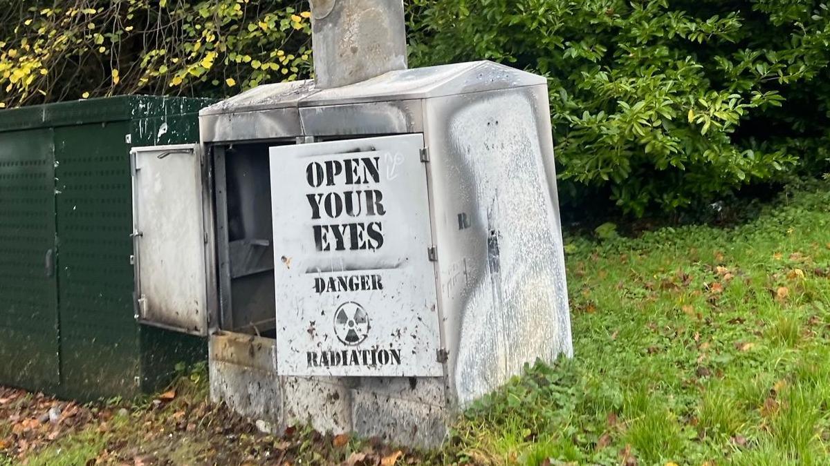 A damaged mast with the doors open. Painting on the doors, says open your eyes. Danger. Radiation.