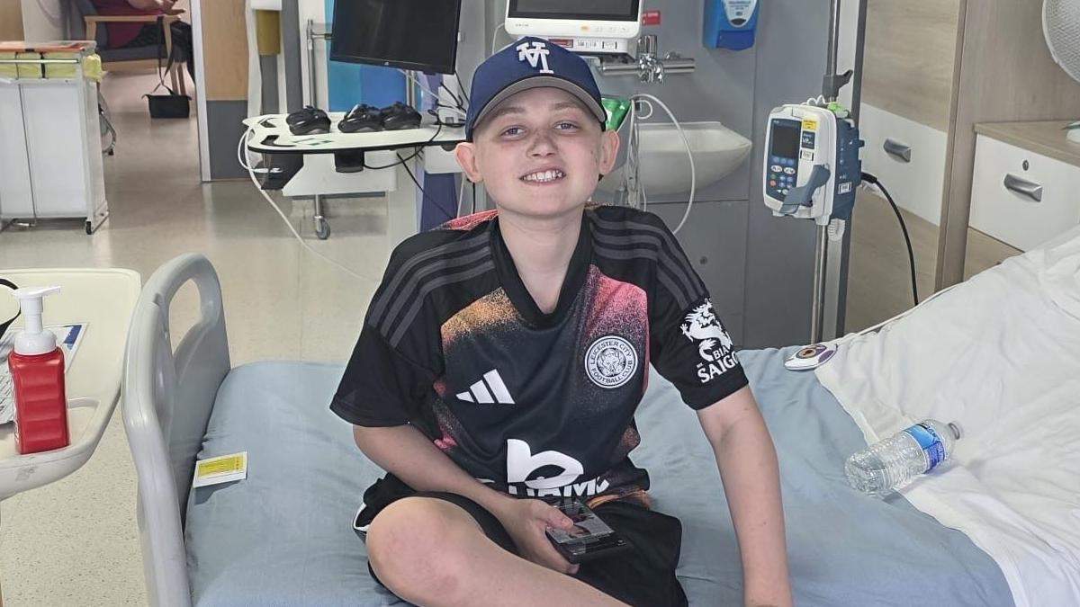 Harrison sat on his hospital bed at the Leicester Royal Infirmary wearing a baseball cap 