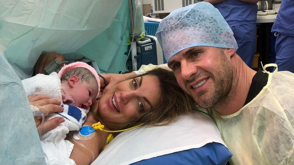 Andrea and Lee in the operating theatre pose for a photograph with their newborn daughter Jemima in 2019