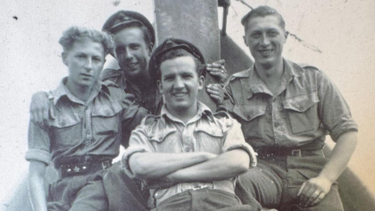 A black and white photo from the 1940s of four servicemen looking at the camera and smiling.
