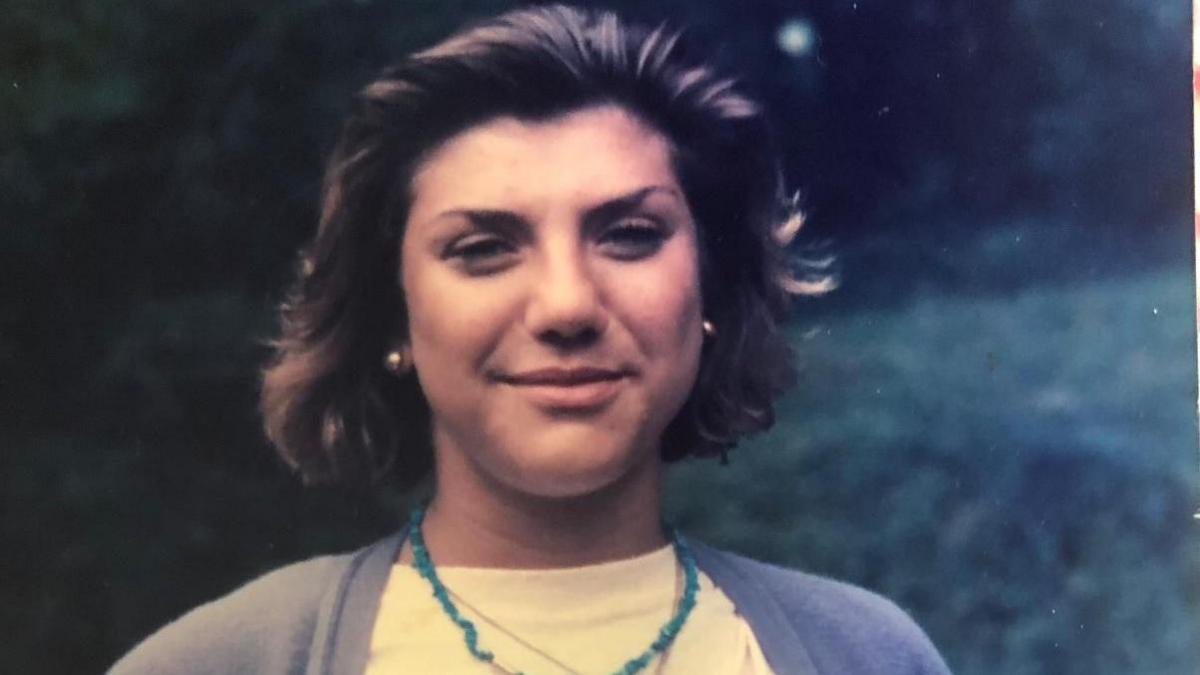 A family photo of Sophie Narme, a young woman with brown hair in a bob, wearing a neutral coloured cardigan and a pale yellow T-shirt with a jade-coloured necklace.