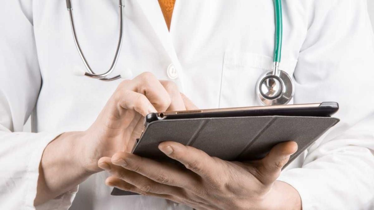 A stock image of a doctor wearing a white coat holding an iPad.