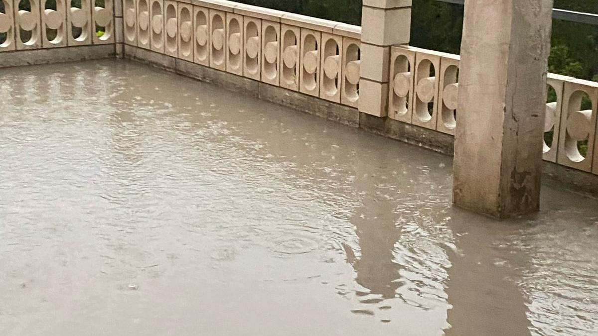 A flooded terrace at a country house. Water covers the terrace which is surrounded by decorative balustrades.