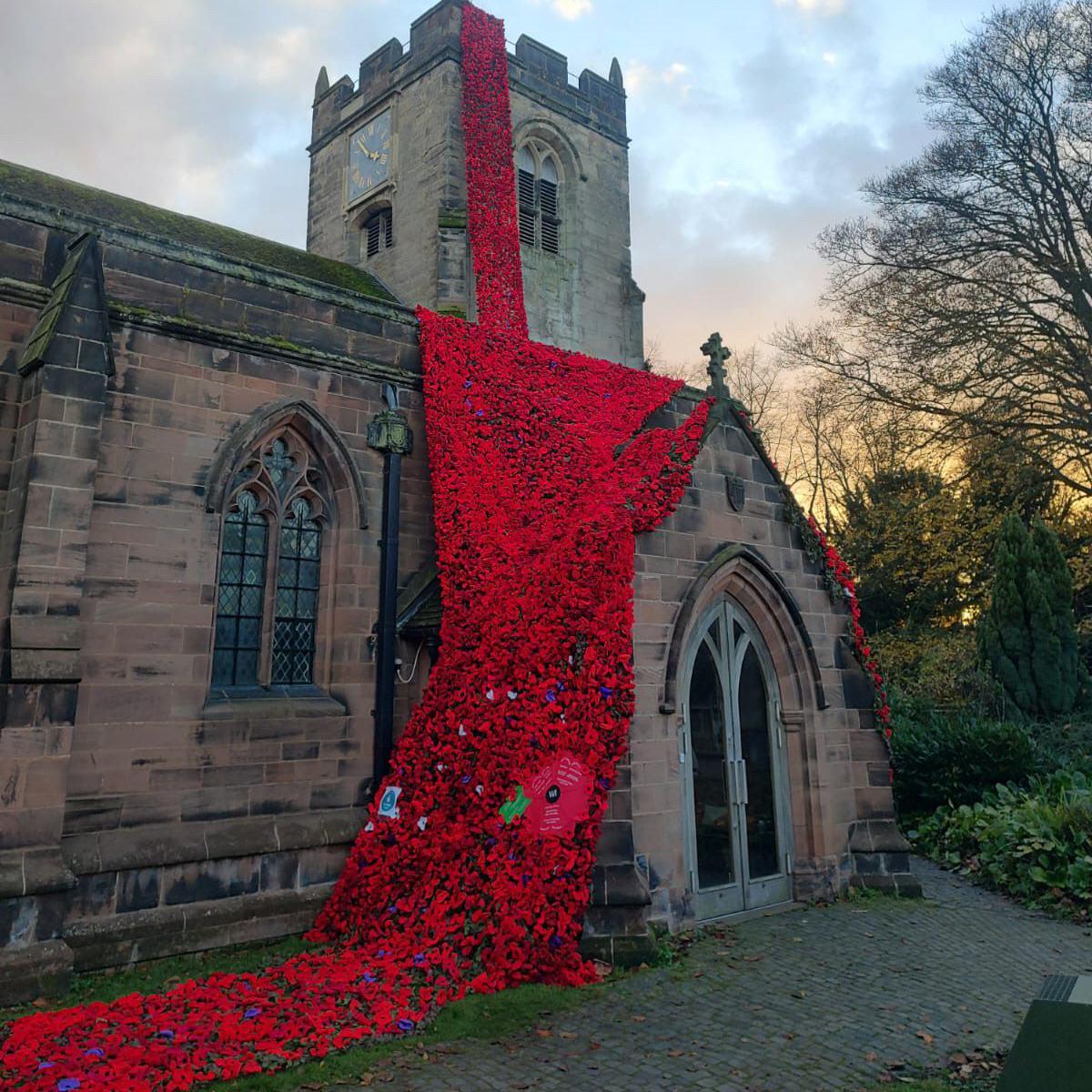 A church covered in knitted poppies from its roof down to the floor.