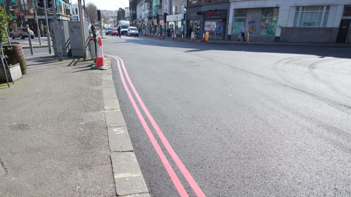 Double red lines running along a black tarmac road.