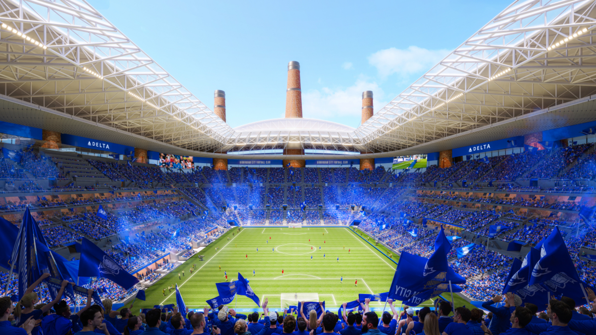 Inside the ground is a sea of blue where fans are seated in this artist impression. The pitch can be seen with players on it. Advertising screen surround the top ring around the ground which is partially covered with a white roof.