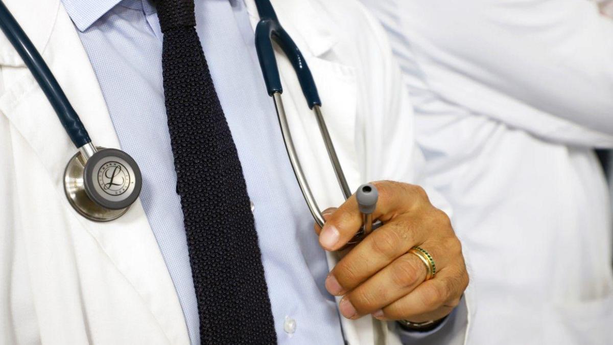 A generic photo of a doctor wearing a shirt, tie and white jacket. They have a stethoscope around their neck. The face is not visible.