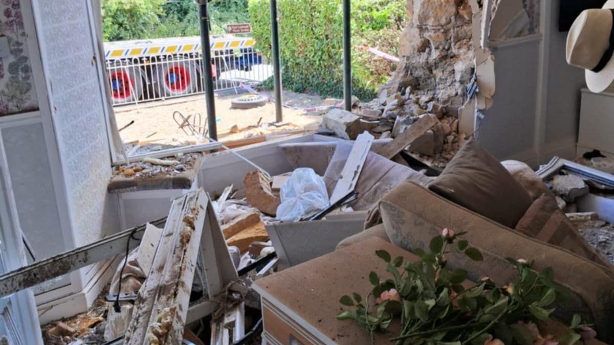 A front room that is filled with rubble and has a big hole in the front.