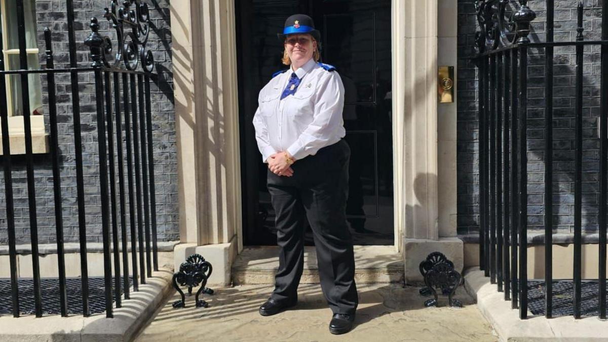 A woman in a PCSO uniform stands outside of number 10 Downing Street. 
