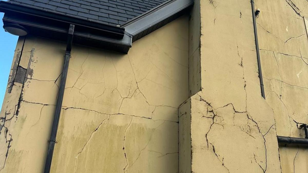 A house with large cracks visible on its side. 