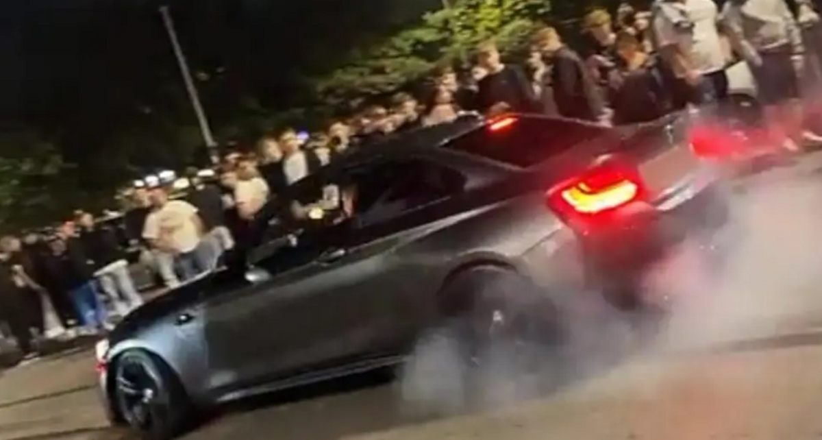 Footage from the car meet of a black car skidding its tyres in front of a large crowd.