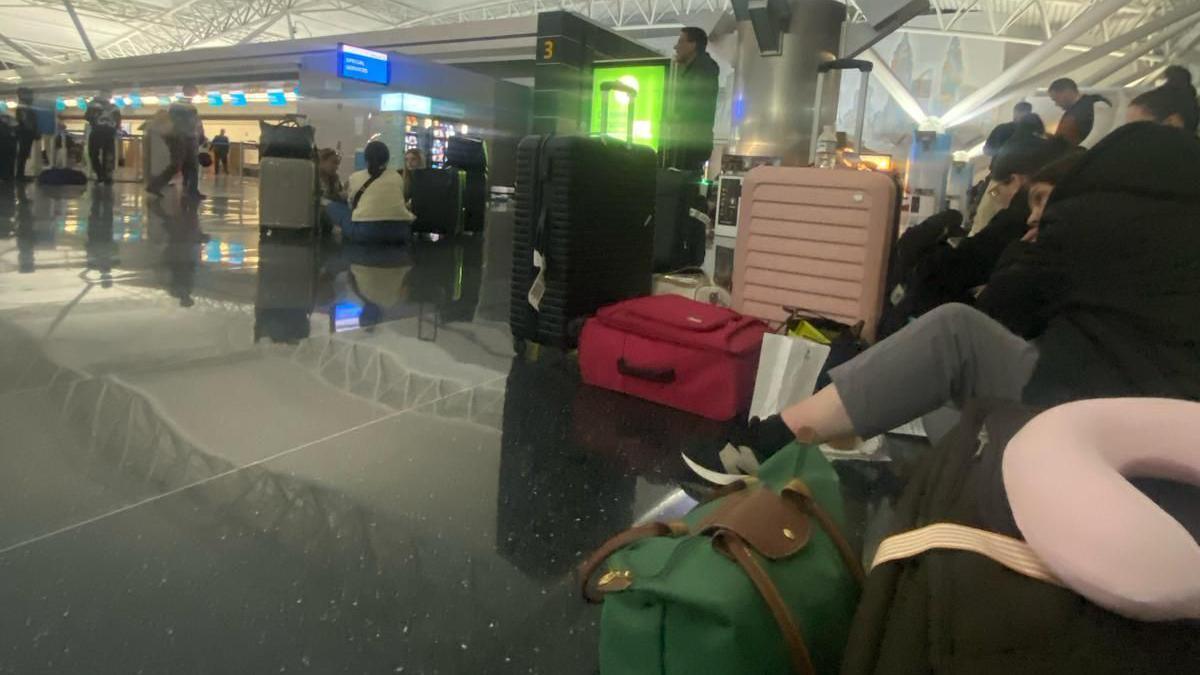 Stranded British Airway passengers with their luggage around them sit on the terminal floor at New York's John F.Kennedy airport on Friday morning