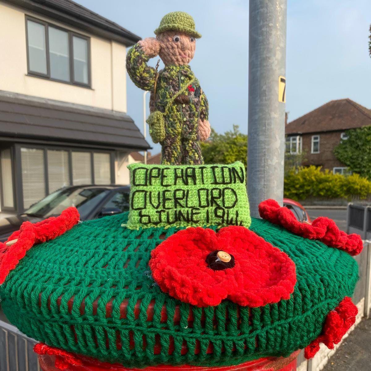 A crochet model of a D-Day soldier surrounded by poppies